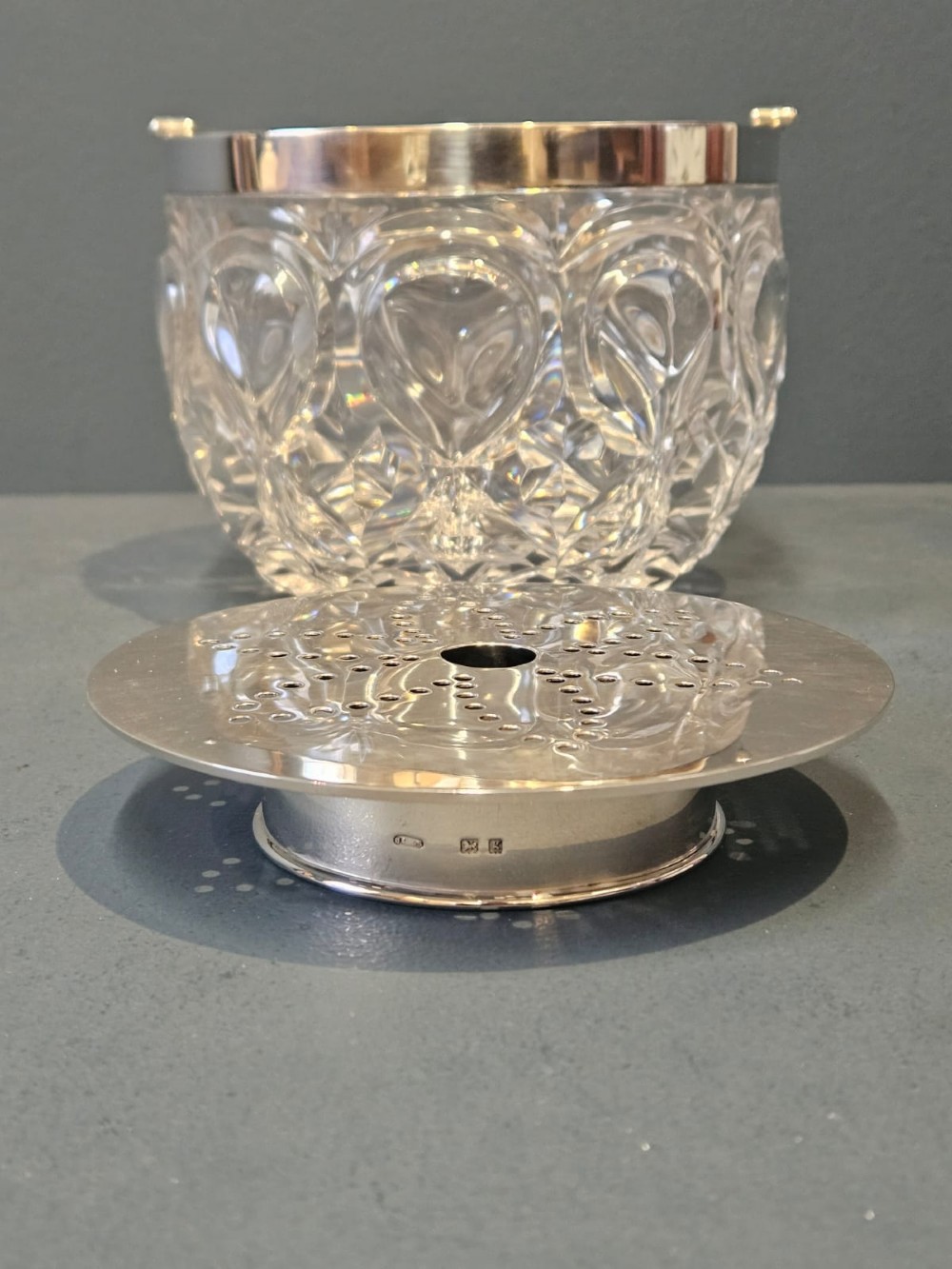 A clear cut crystal ice pail featuring an arched decorative motif, fitted with a silver rim and a slender swing handle. View VII