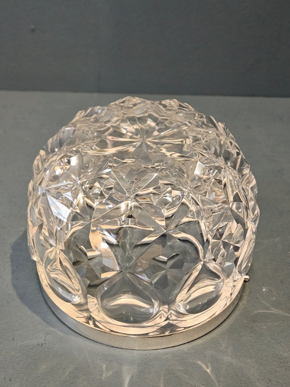 A clear cut crystal ice pail featuring an arched decorative motif, fitted with a silver rim and a slender swing handle. View IX