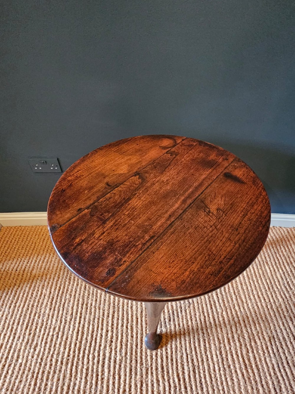 A round Georgian elm cricket table with three tapered legs terminating in pad feet and a triangular deep apron. View II