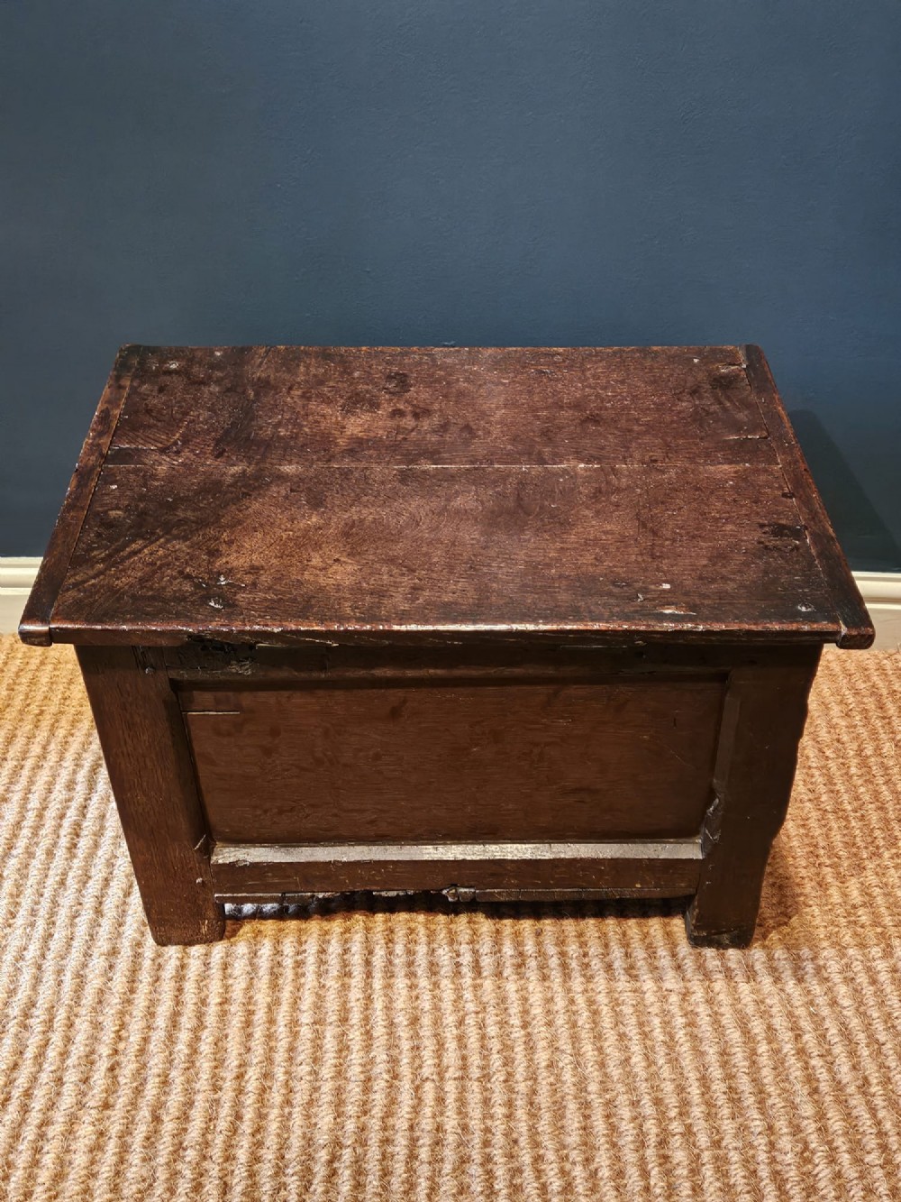 A small 17th-century dark oak coffer featuring a single front panel, a hinged plank top, and a wrought iron lock plate. View VIII