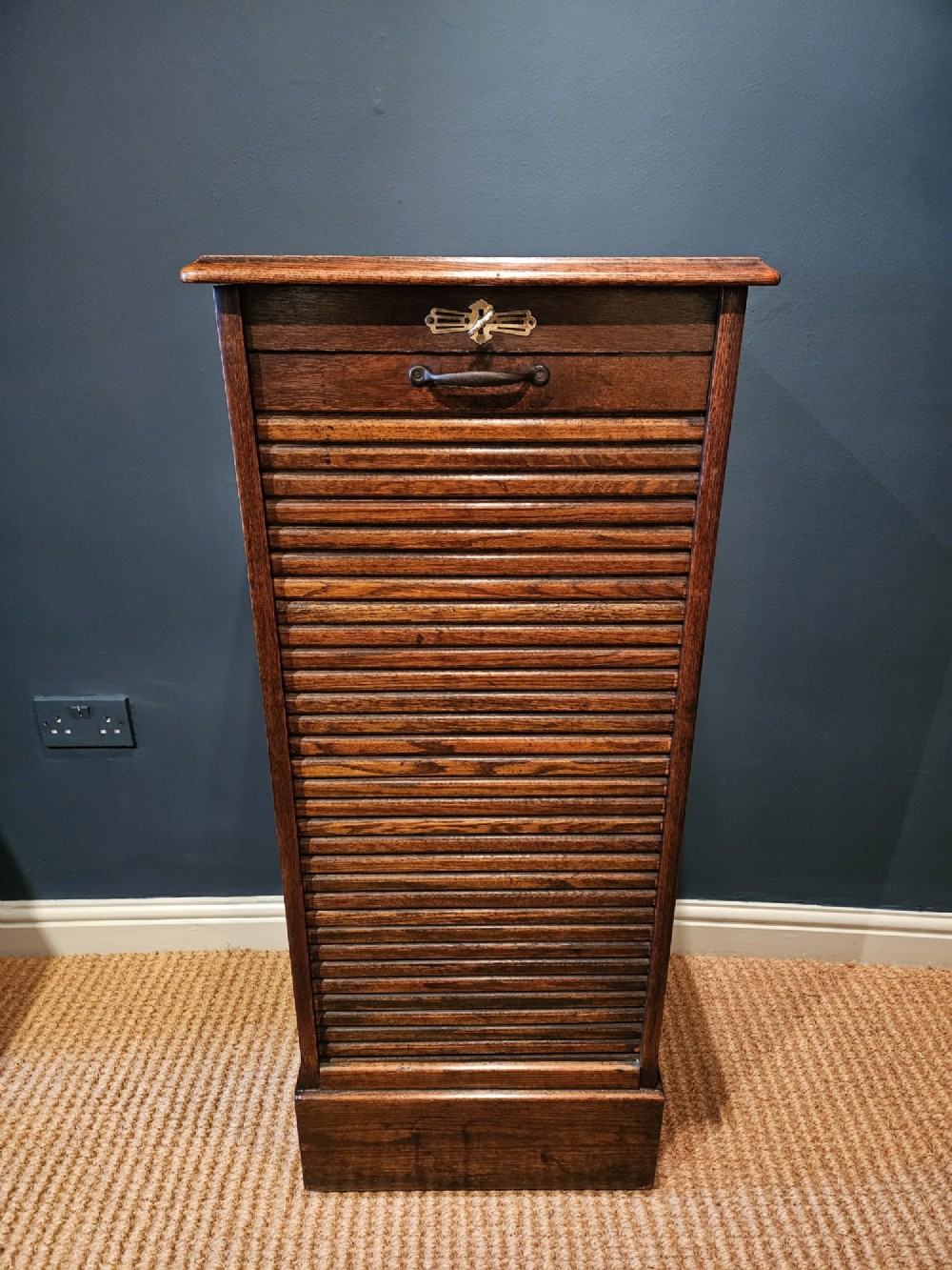 A tall Victorian medium brown oak filing cabinet featuring internal document trays with brass label holders and a top key lock. View II