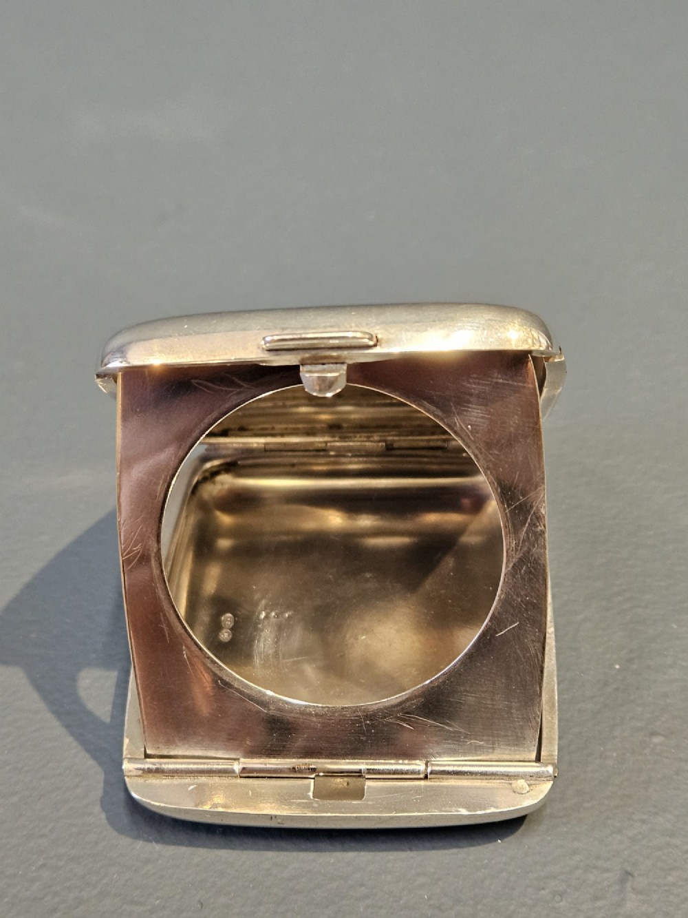 A squarish sterling silver pocket watch case with rounded corners, featuring a blue and white enamel border around the top lid and a thumbpiece latch. View IV