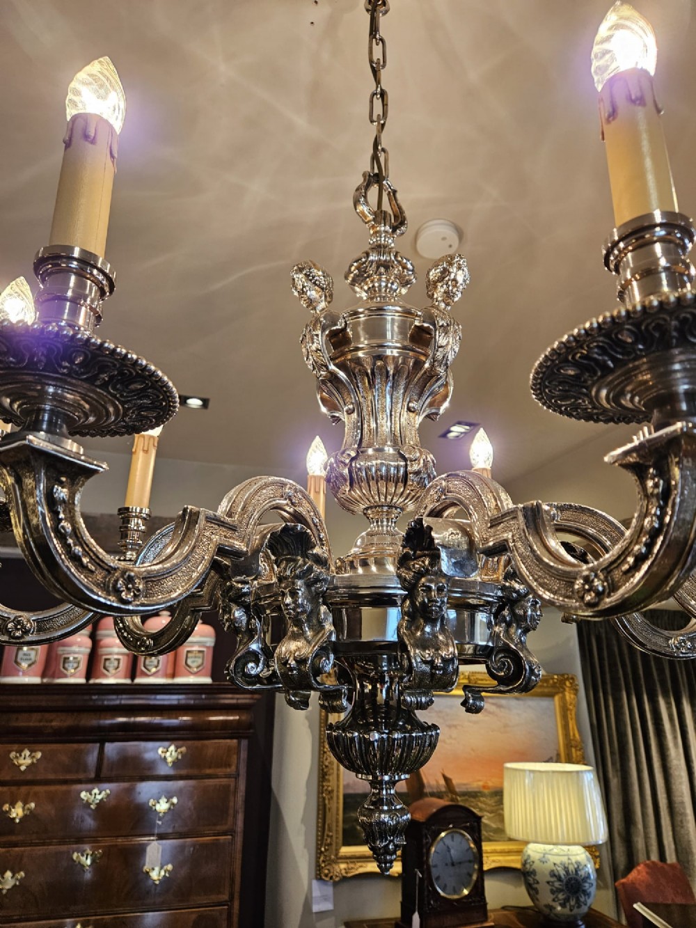 An Edwardian eight-arm nickel-plated chandelier featuring decorative central baluster detailing, S-scroll branches, and faux candle sleeves. View III