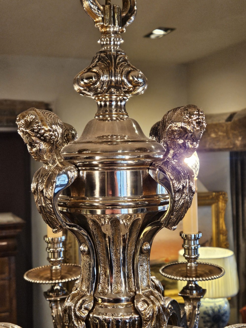 An Edwardian eight-arm nickel-plated chandelier featuring decorative central baluster detailing, S-scroll branches, and faux candle sleeves. View V