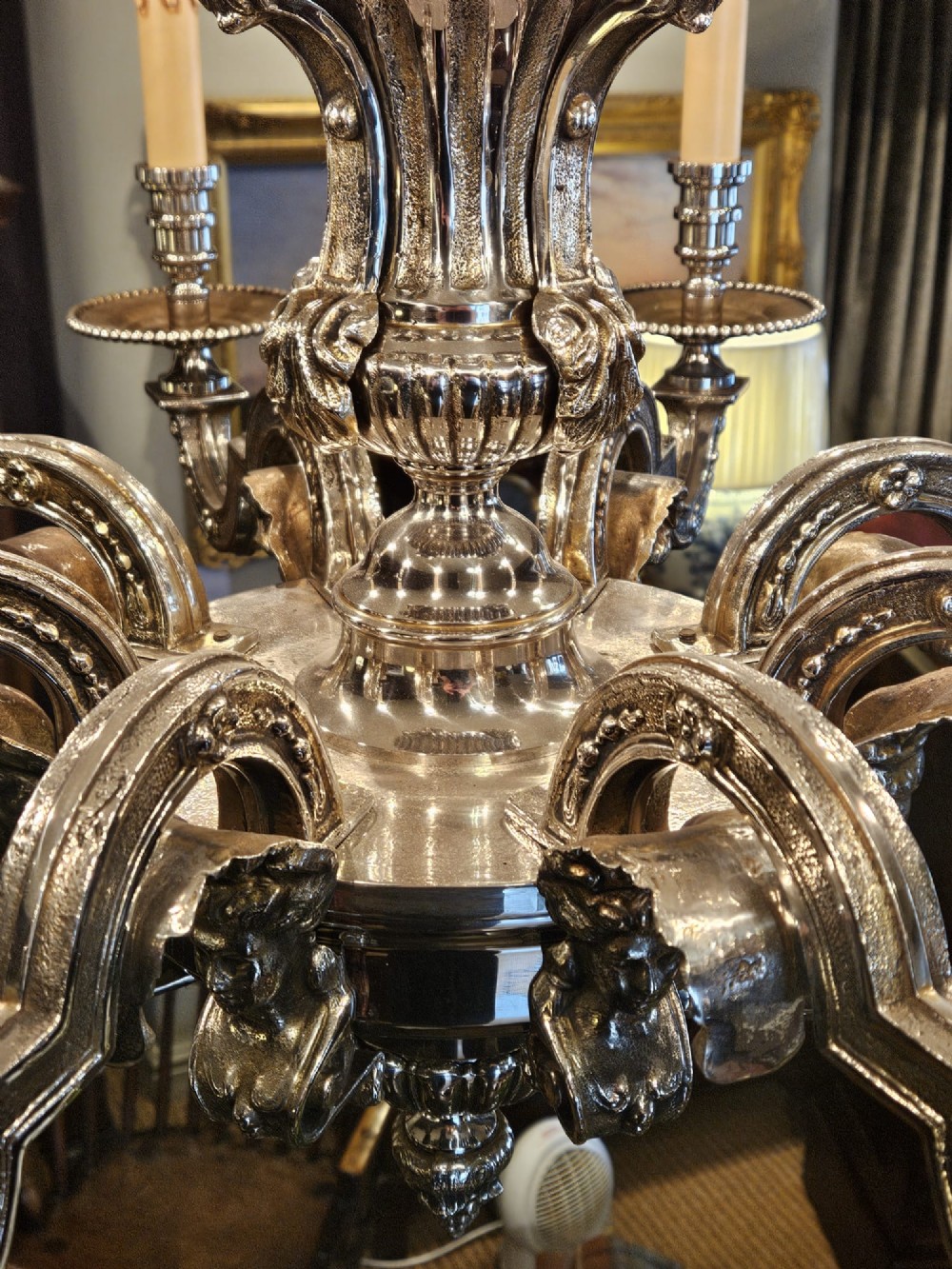 An Edwardian eight-arm nickel-plated chandelier featuring decorative central baluster detailing, S-scroll branches, and faux candle sleeves. View VII
