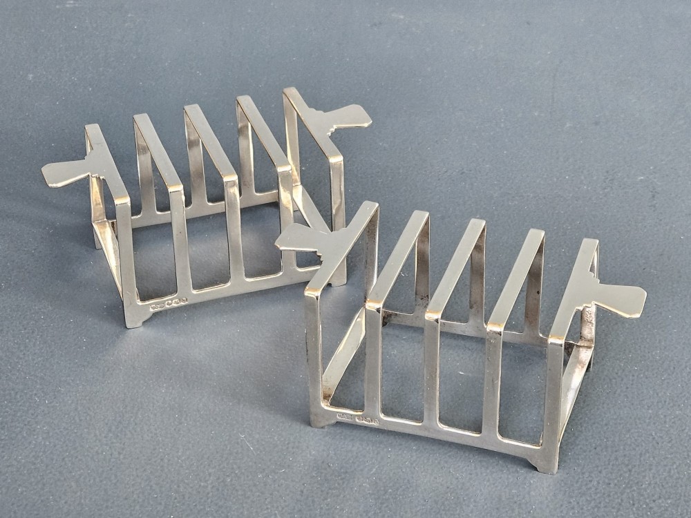 A matching pair of silver six-slice toast racks made by Mappin and Webb with geometric handles and stamped hallmarks.