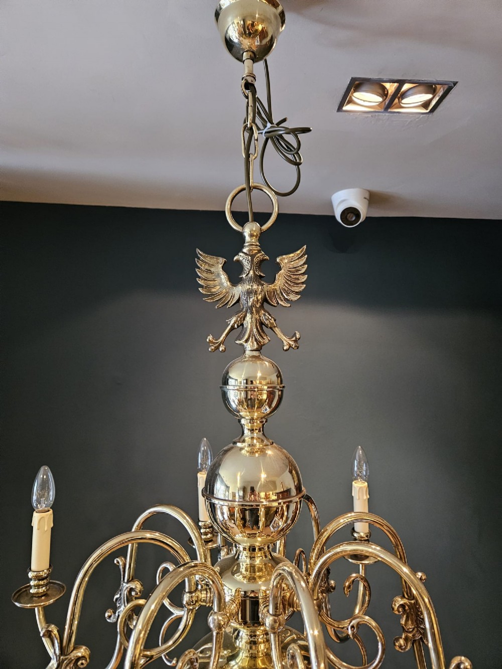 An Edwardian-style polished brass eight-arm chandelier featuring an eagle finial, central baluster stem, scrolling branches, and faux candle light sockets. View VI