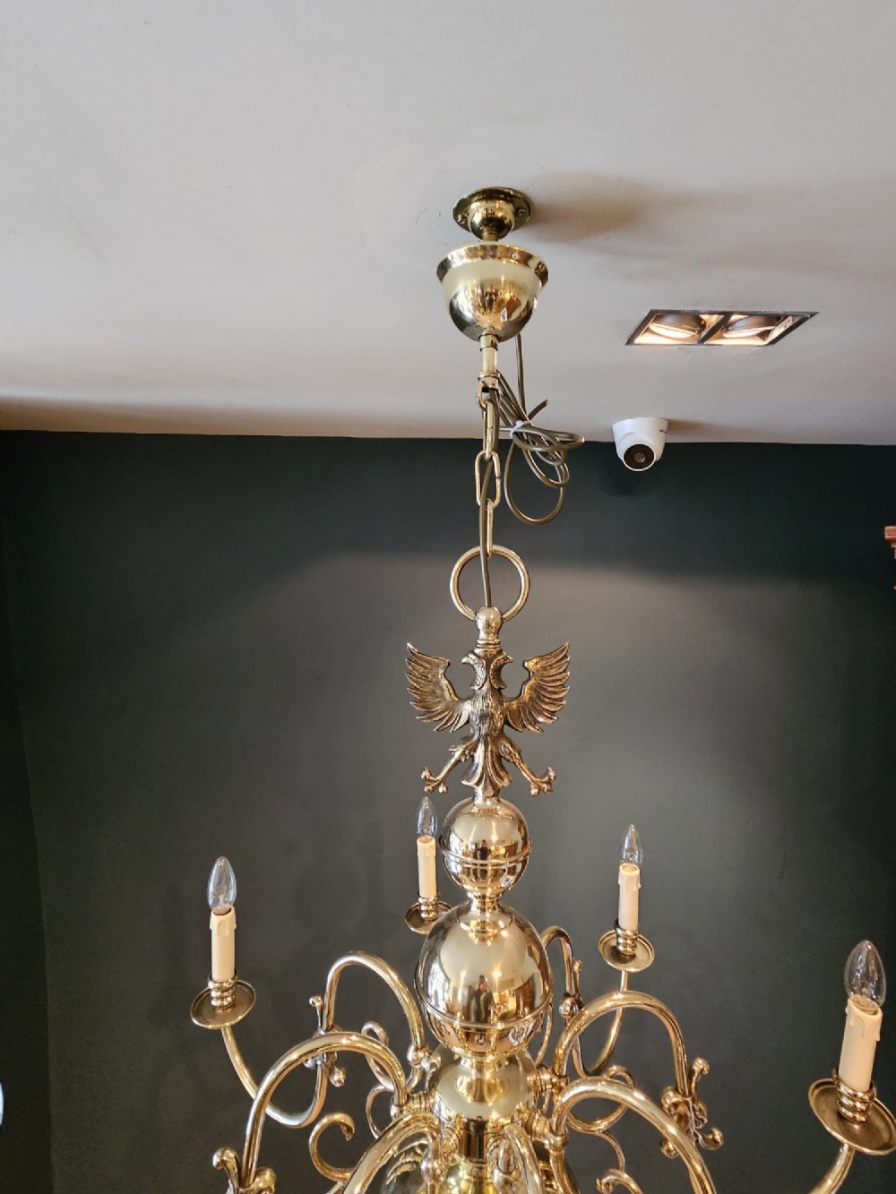 An Edwardian-style polished brass eight-arm chandelier featuring an eagle finial, central baluster stem, scrolling branches, and faux candle light sockets. View VII