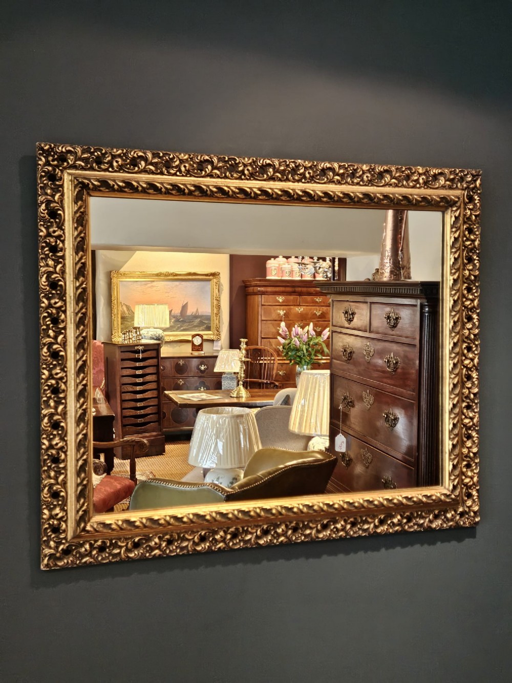 A large rectangular Victorian gilt mirror featuring a heavily carved timber frame with a gold leaf finish.