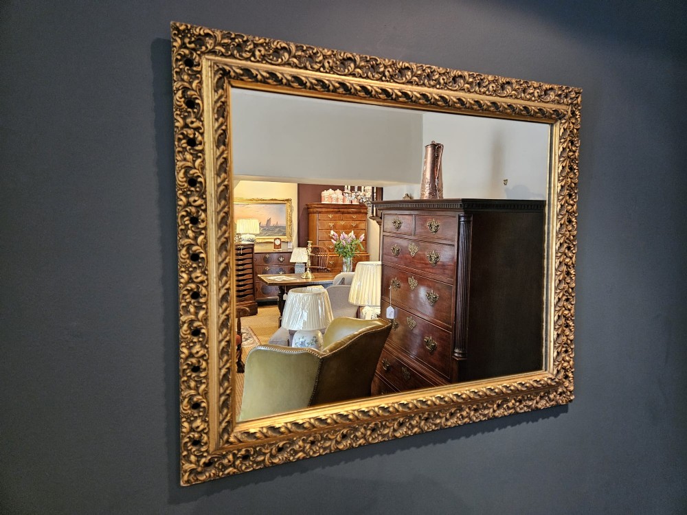 A large rectangular Victorian gilt mirror featuring a heavily carved timber frame with a gold leaf finish. View II
