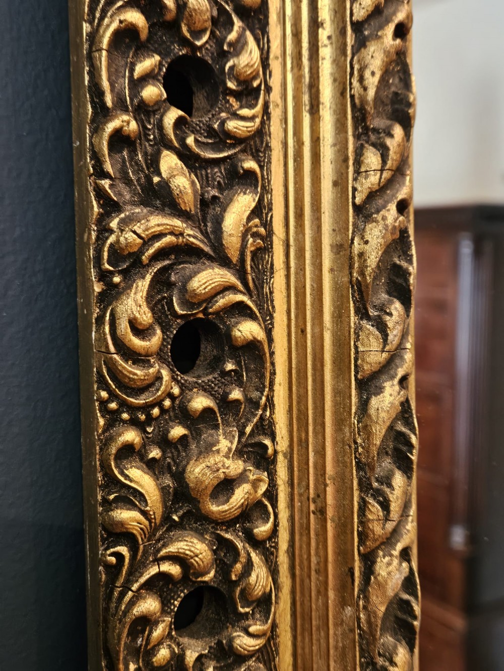 A large rectangular Victorian gilt mirror featuring a heavily carved timber frame with a gold leaf finish. View IV