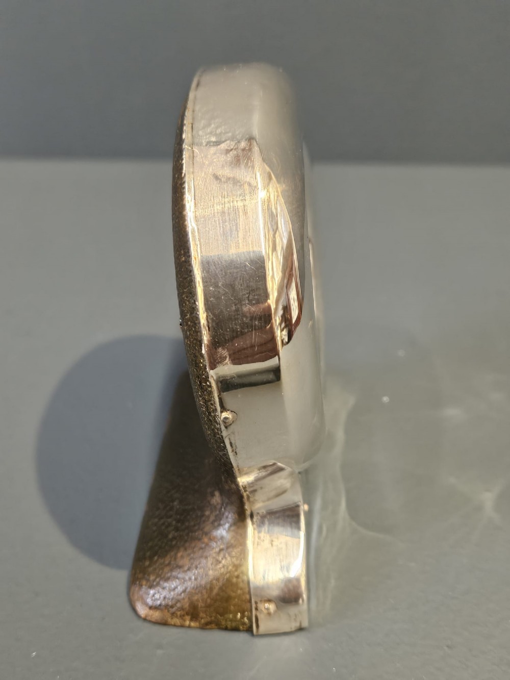 A circular sterling silver pocket watch holder with Chester hallmarks, featuring a recessed green velvet interior bezel and a shaped base. View V