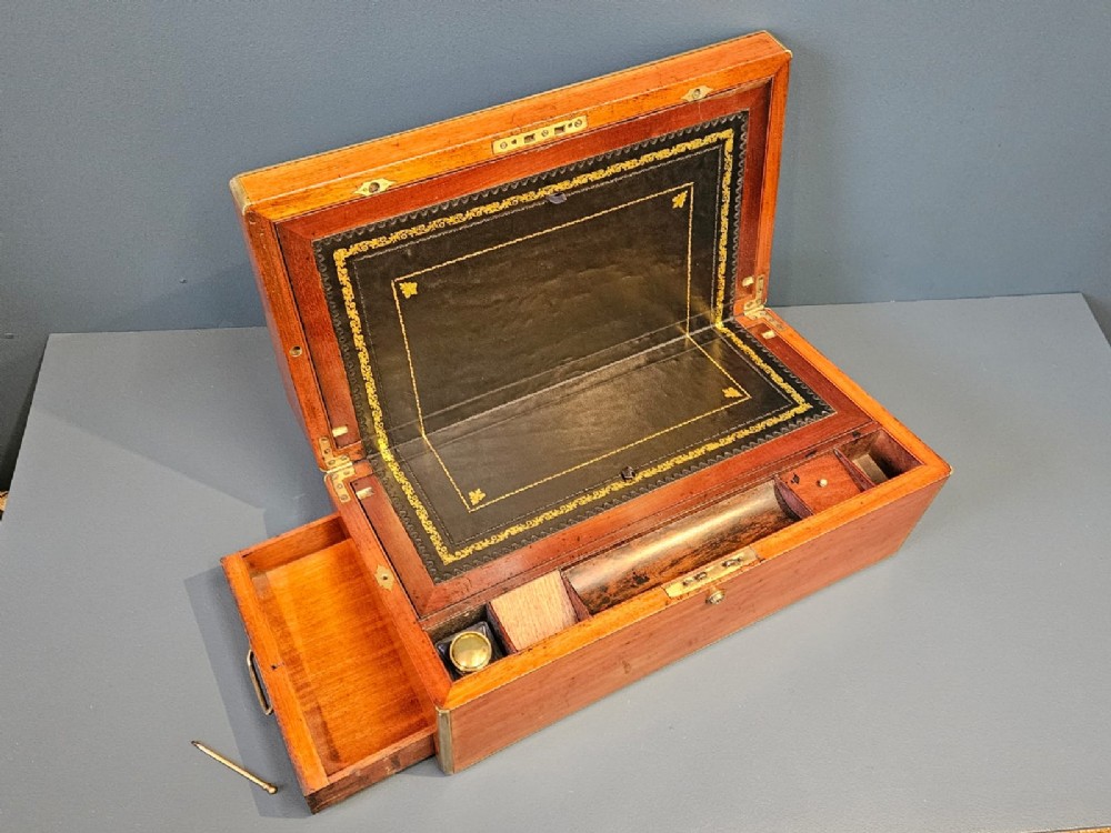 An open Victorian mahogany writing slope featuring a gold-tooled black leather insert, internal compartments, and an extended side drawer.
