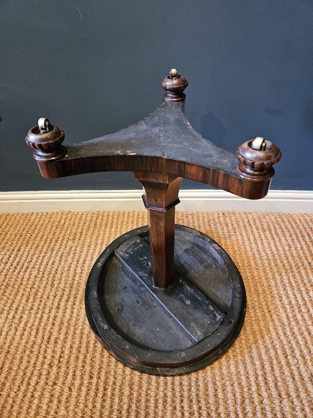A round antique Regency rosewood occasional table featuring a rich grain, a central faceted pedestal column, and a tri-form platform base resting on carved feet. View VII