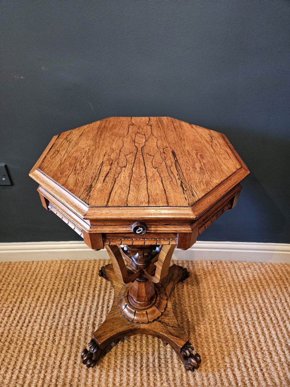 A William IV rosewood octagonal sewing work table featuring a tapered trumpet column supported by a carved quadform base with scroll feet. View V