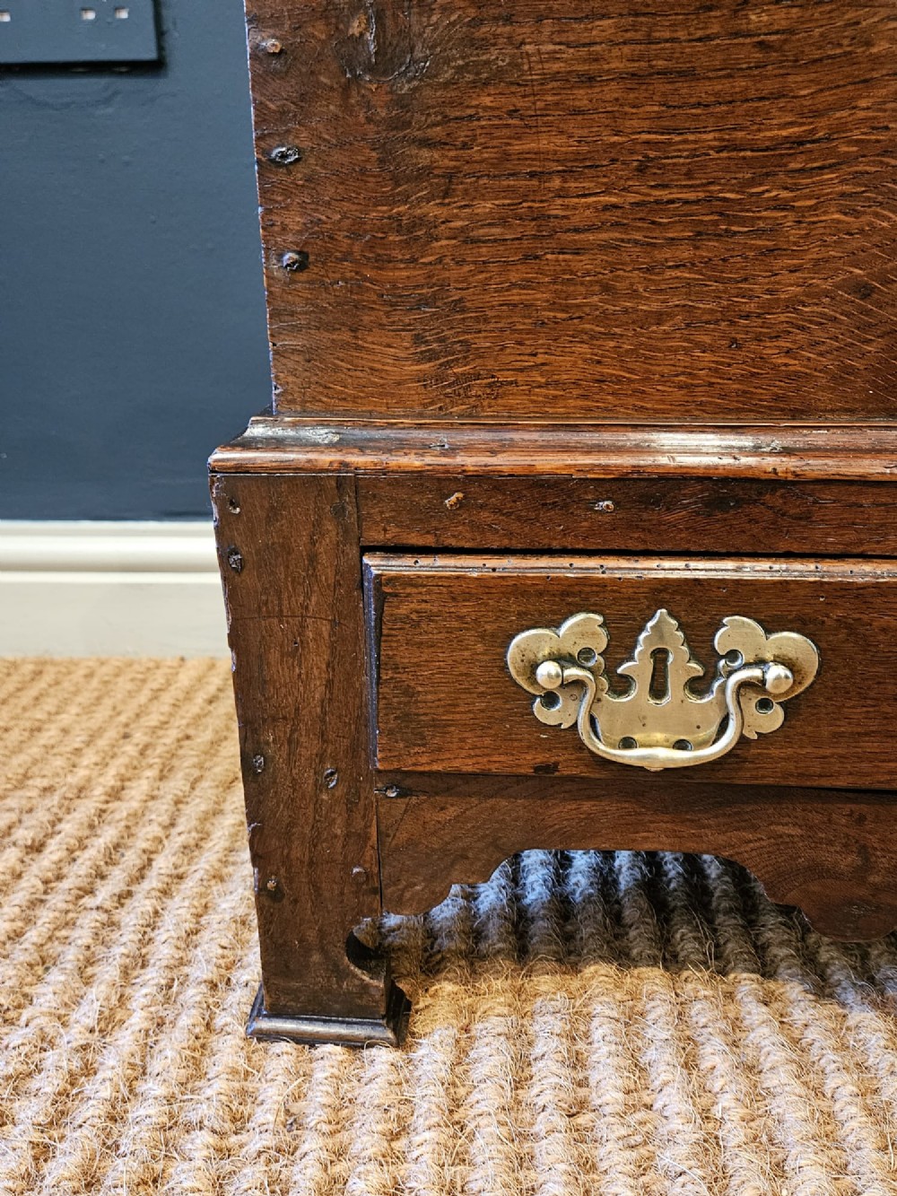 An antique 18th-century George II Welsh oak coffer bach with a hinged top lid, lower drawer, shaped apron, and brass escutcheons. View III