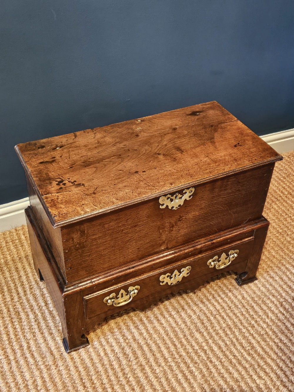An antique 18th-century George II Welsh oak coffer bach with a hinged top lid, lower drawer, shaped apron, and brass escutcheons. View VII