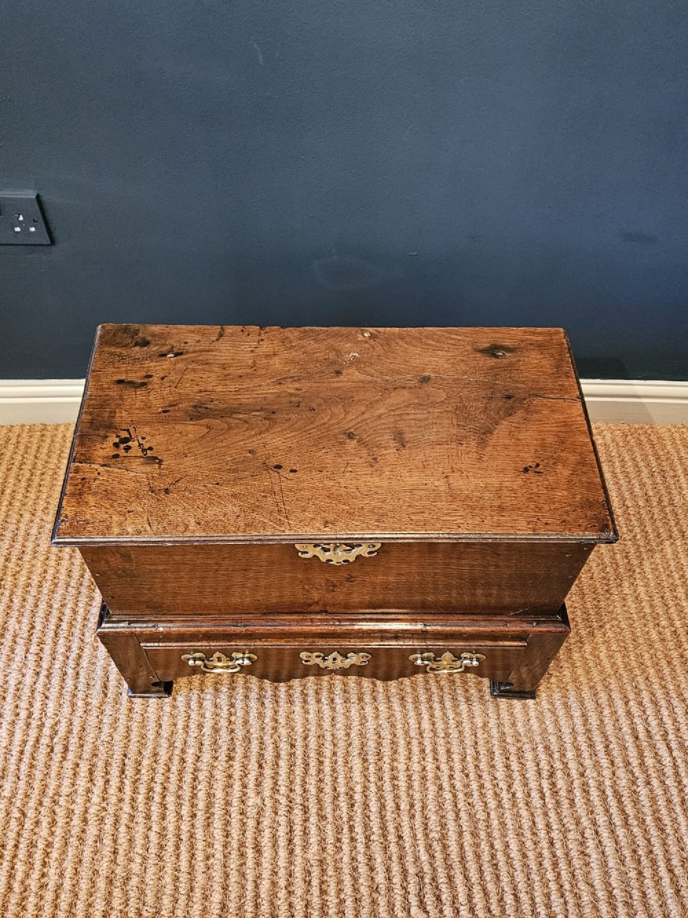 An antique 18th-century George II Welsh oak coffer bach with a hinged top lid, lower drawer, shaped apron, and brass escutcheons. View VIII