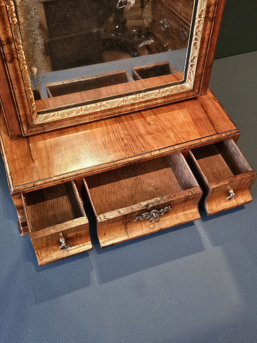 An 18th-century George II figured walnut toilet mirror featuring an adjustable frame with a gilded inner slip moulding above a single-drawer wooden base. View IV