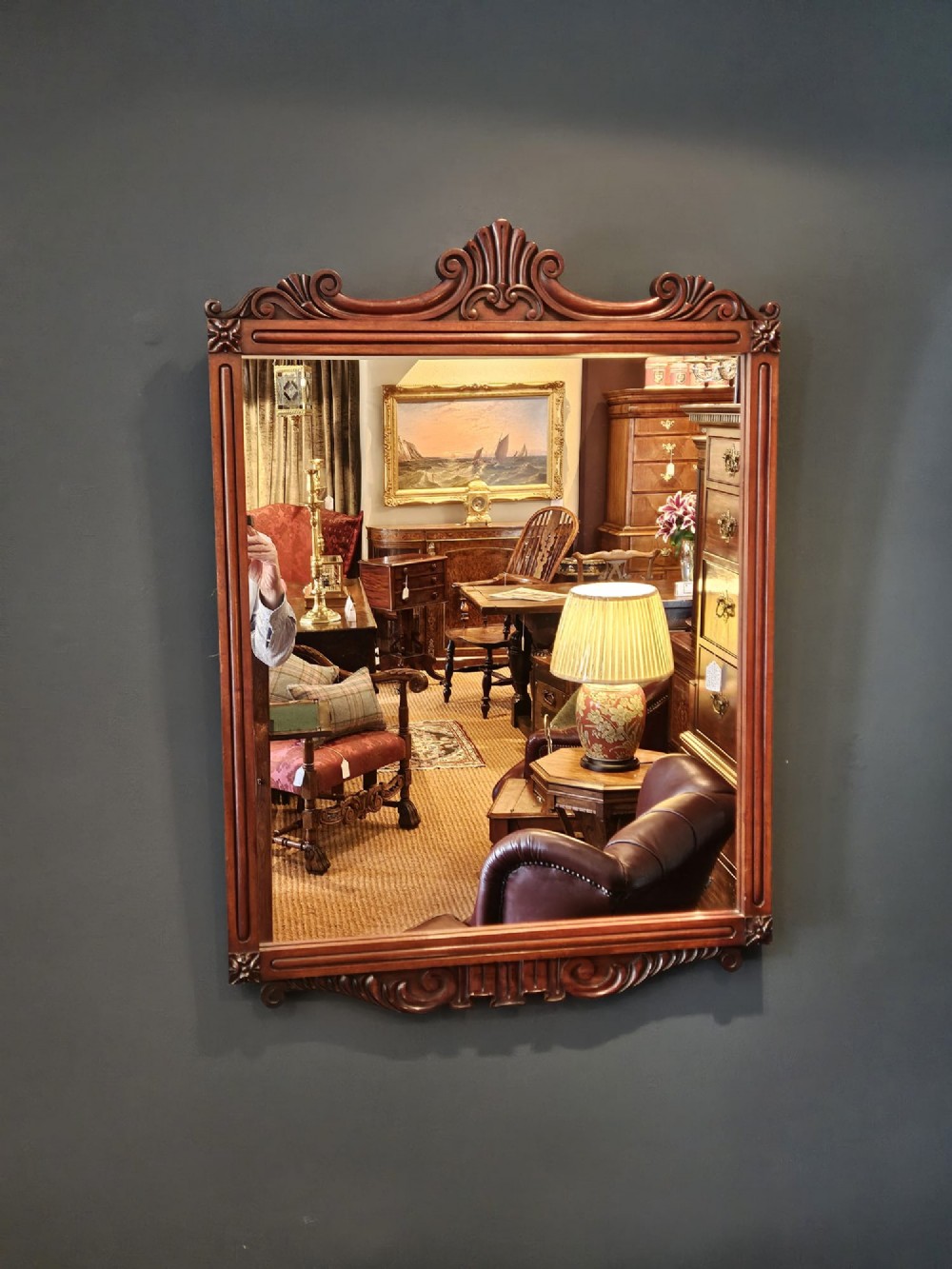 A rectangular Victorian mahogany wall mirror featuring a carved pediment crest and fluted side pillars.