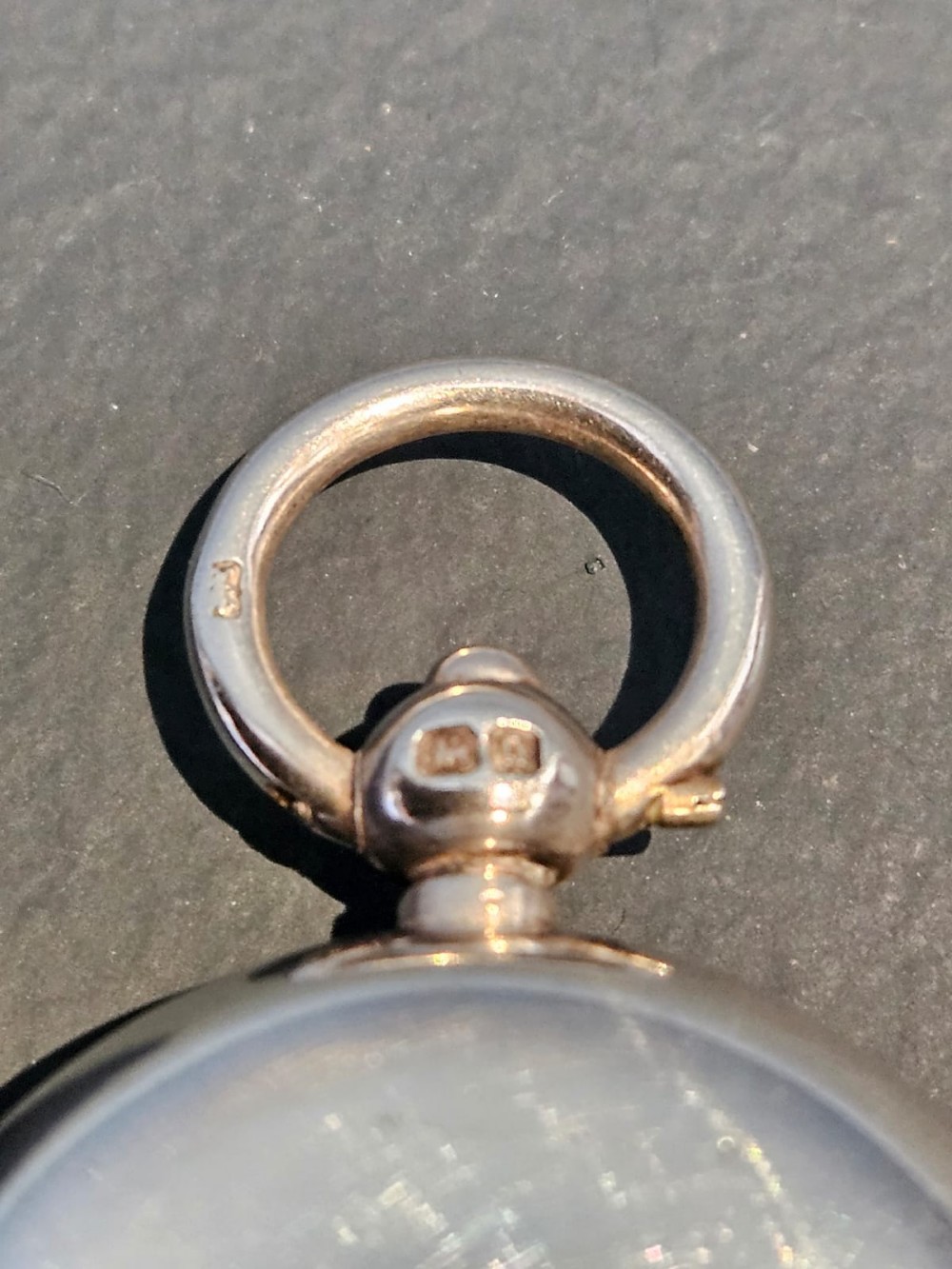 A circular polished sterling silver sovereign case with a top suspension ring and hallmarked stem. View III