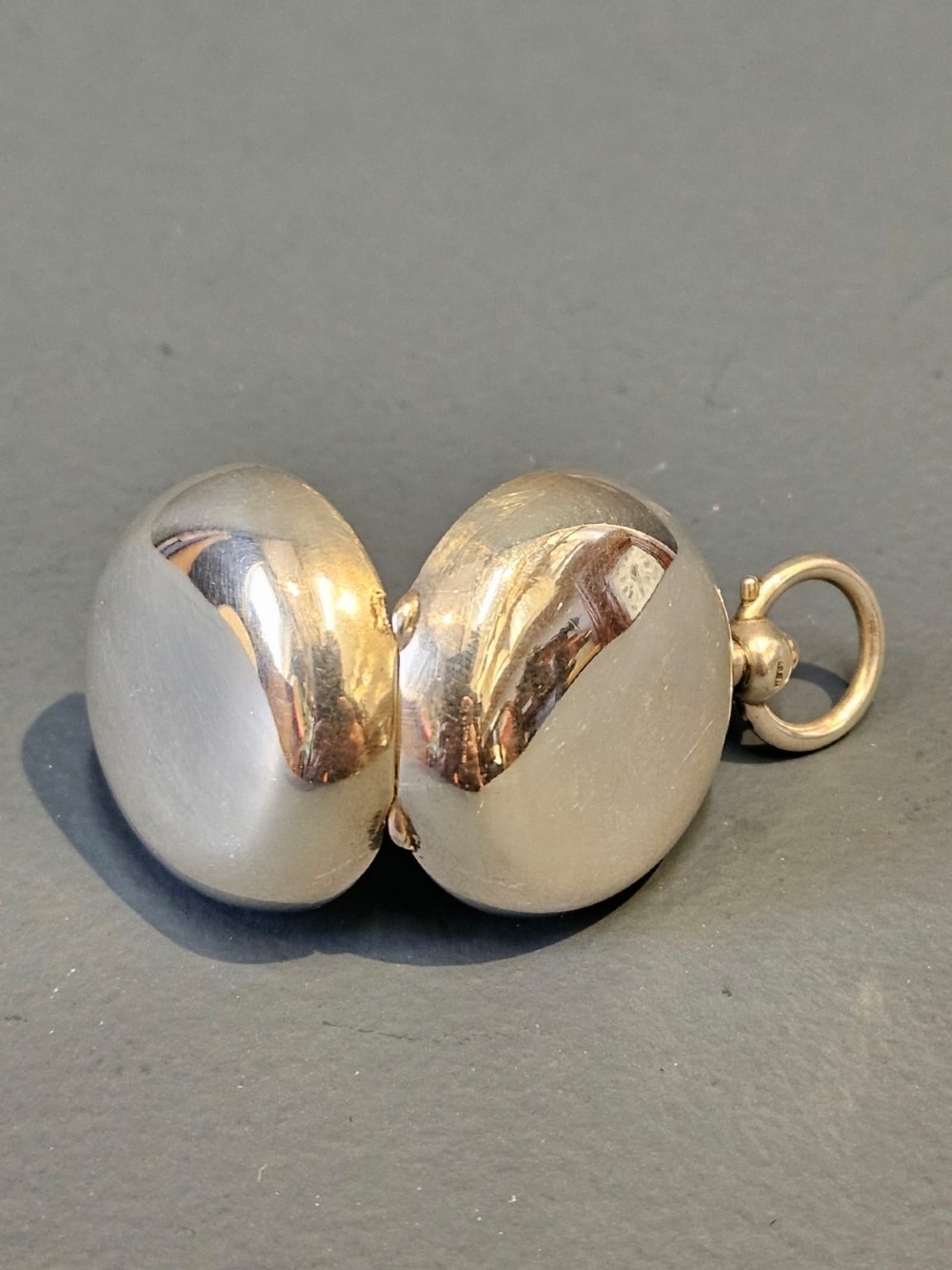 A circular polished sterling silver sovereign case with a top suspension ring and hallmarked stem. View IV