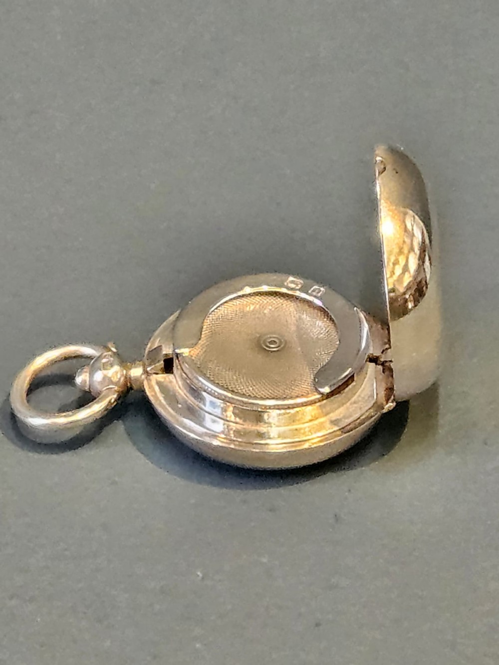 A circular polished sterling silver sovereign case with a top suspension ring and hallmarked stem. View V