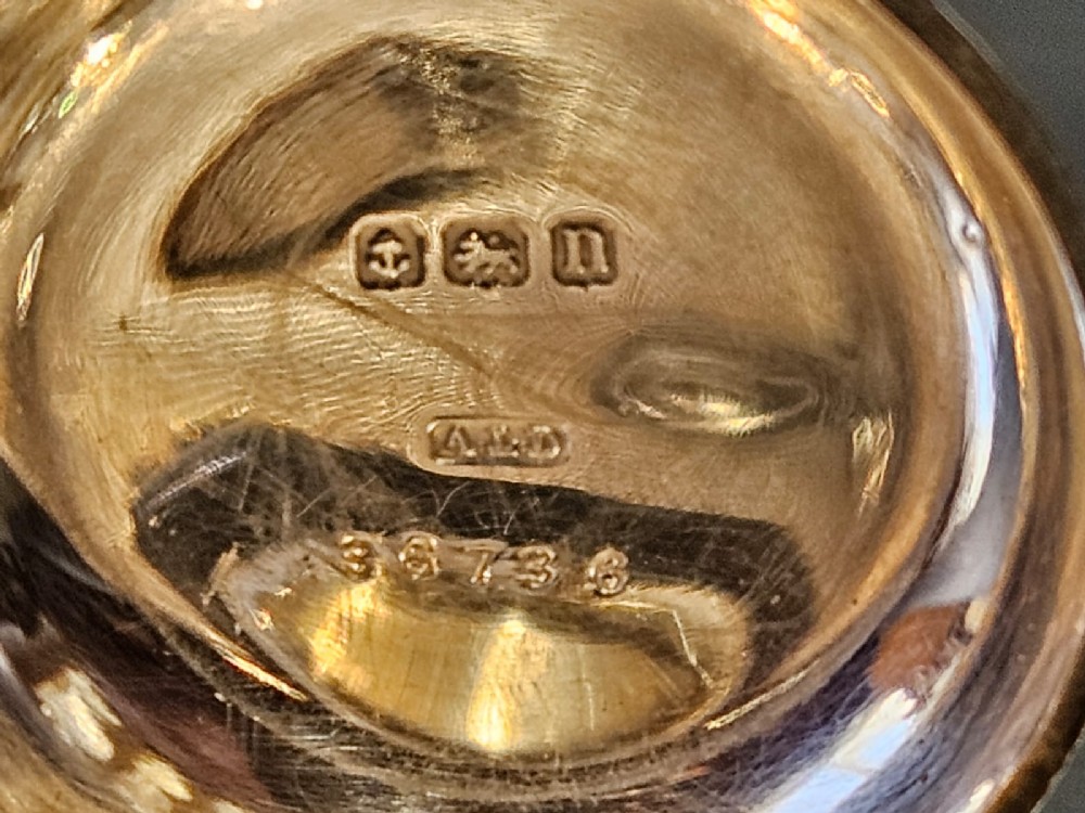 A circular polished sterling silver sovereign case with a top suspension ring and hallmarked stem. View VI