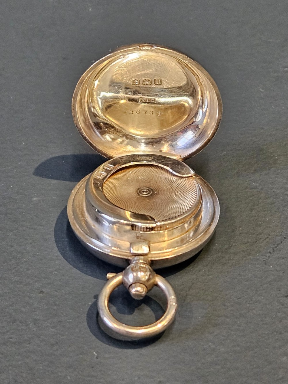 A circular polished sterling silver sovereign case with a top suspension ring and hallmarked stem. View VII