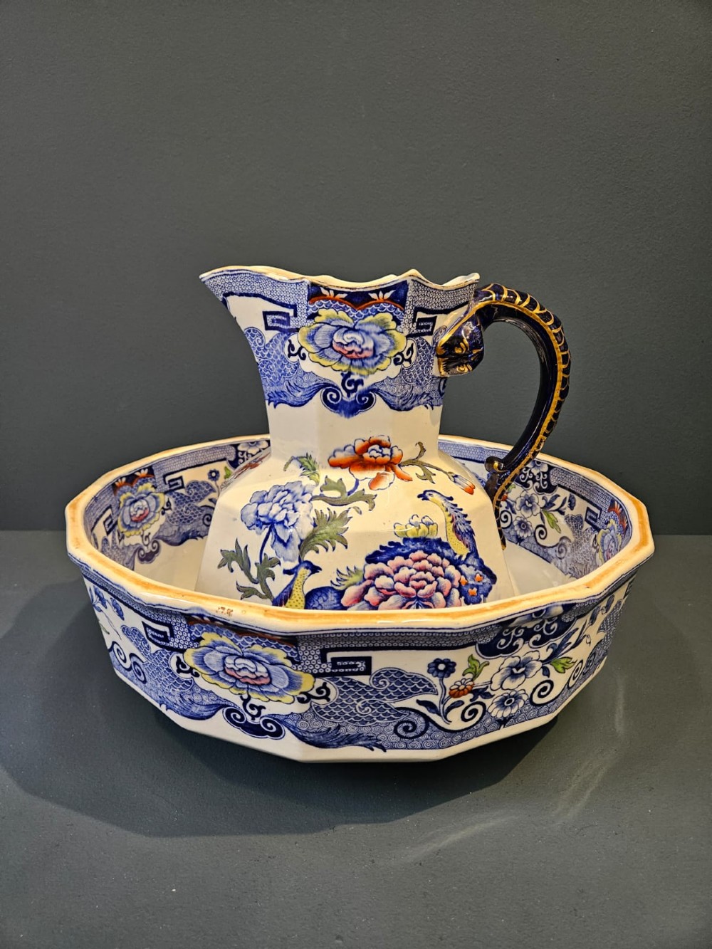 An octagonal Masons ironstone jug and matching wash basin decorated with polychrome floral Chinoiserie patterns and a cobalt blue gilded handle.