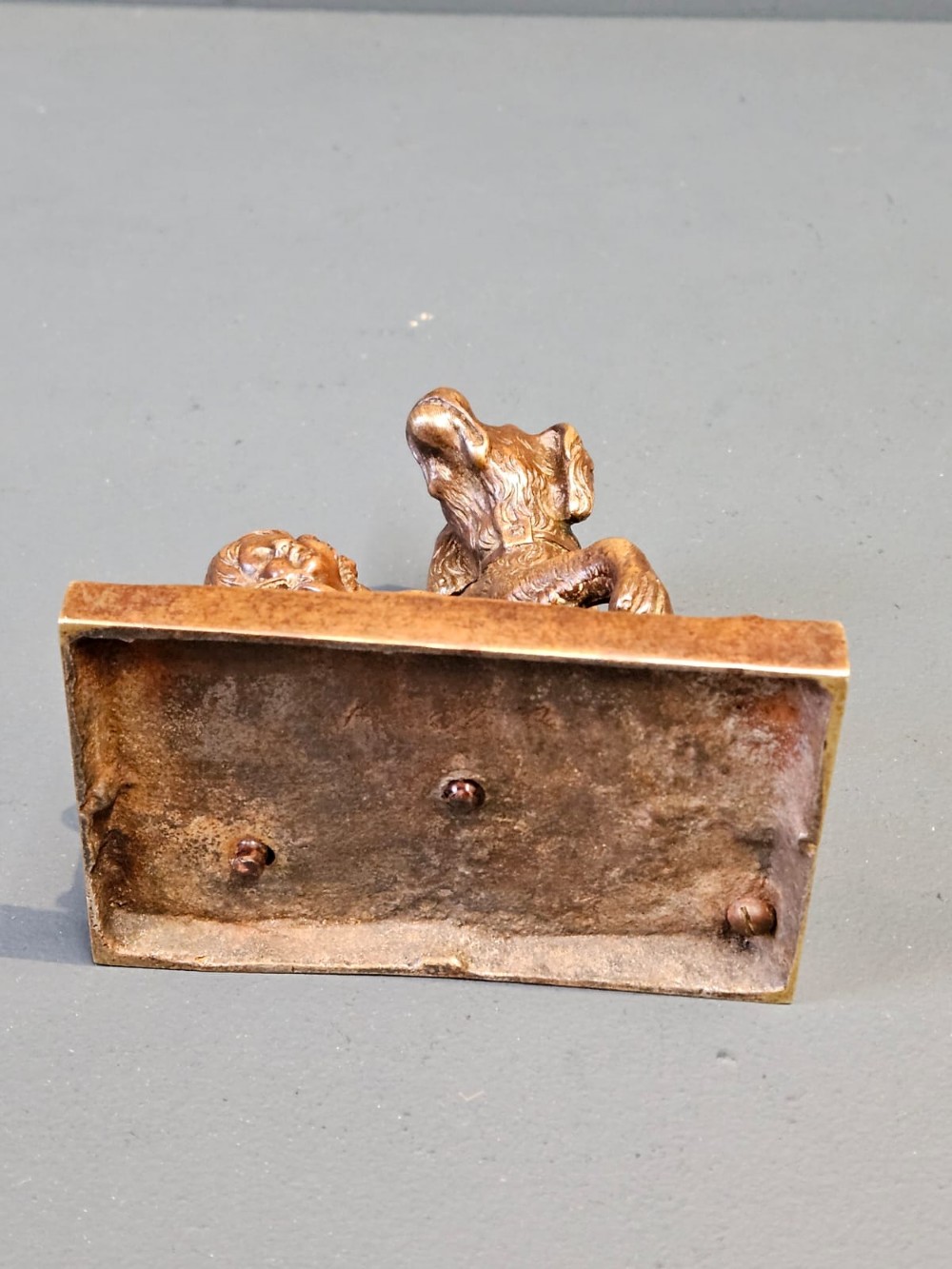 An Edwardian bronze sculpture depicting a sleeping child resting beside an alert dog on a rectangular relief base. View VII