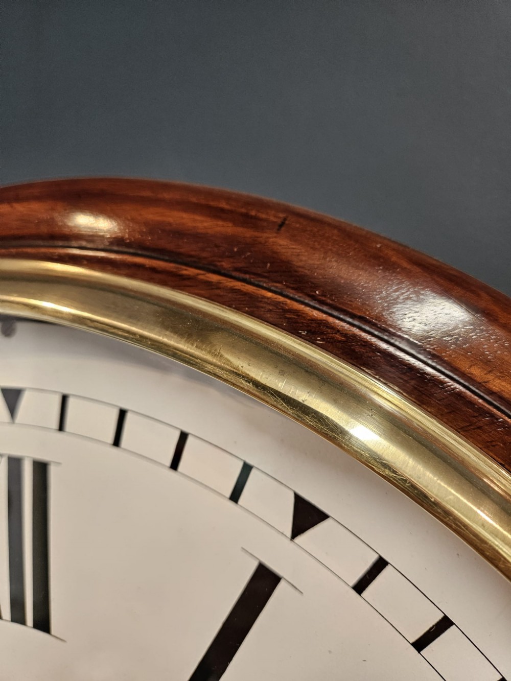 A circular Victorian wall clock featuring a mahogany wooden frame, a white dial with black Roman numerals, spade hands, and a brass bezel. View III