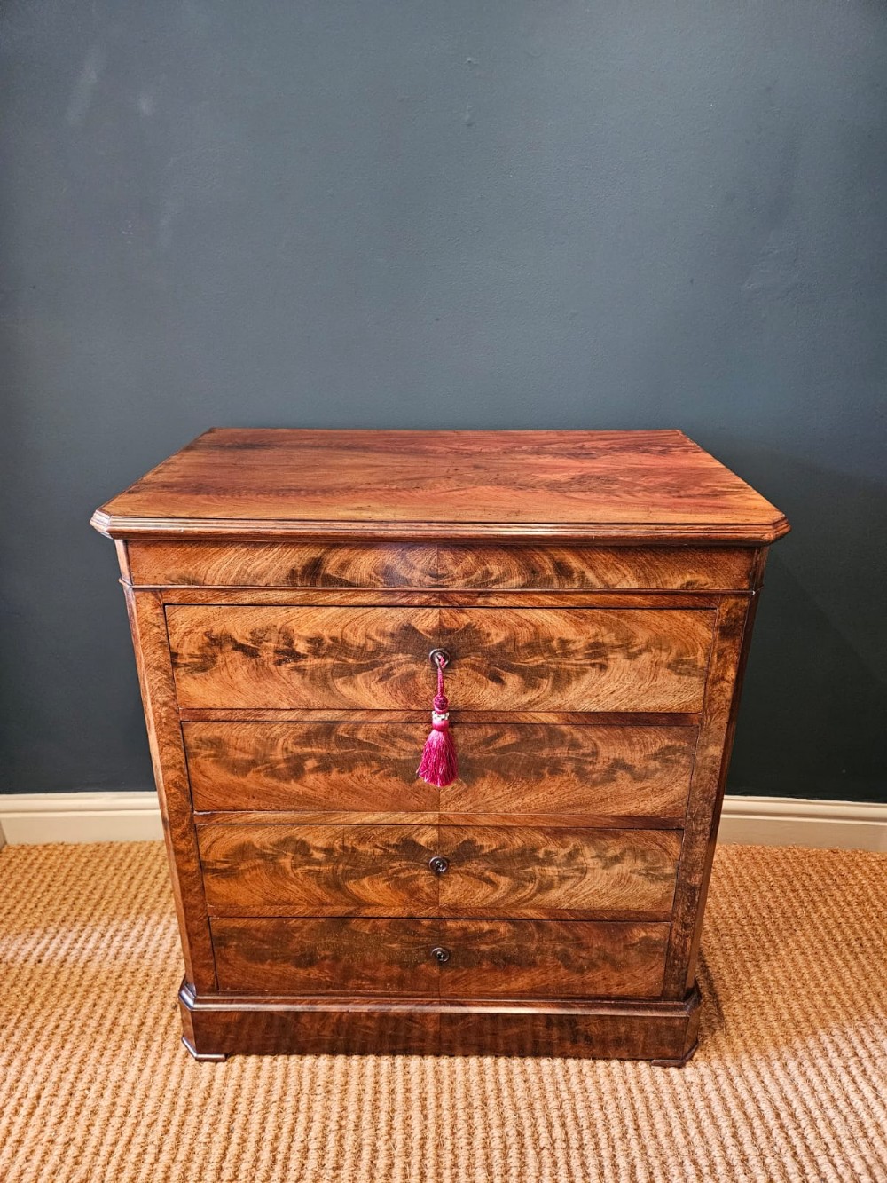 A 19th-century figured mahogany chest of drawers featuring four drawers, flame timber veneer pattern, and a solid plinth base.