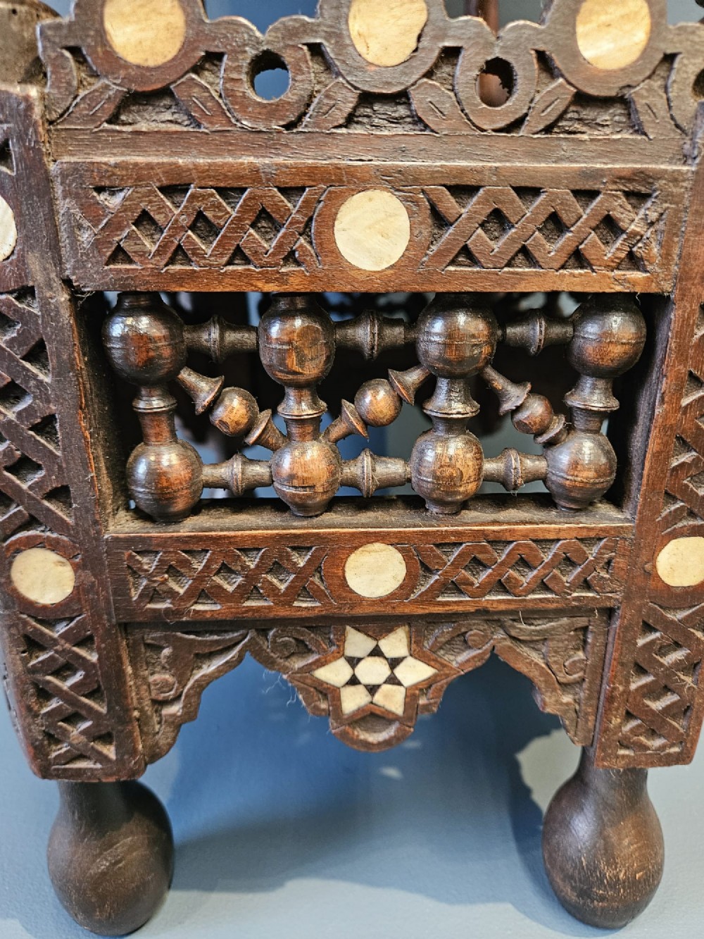 An octagonal dark wood Moorish table featuring carved geometric lattice panels, horseshoe arches, and inlaid bone star motifs. View III