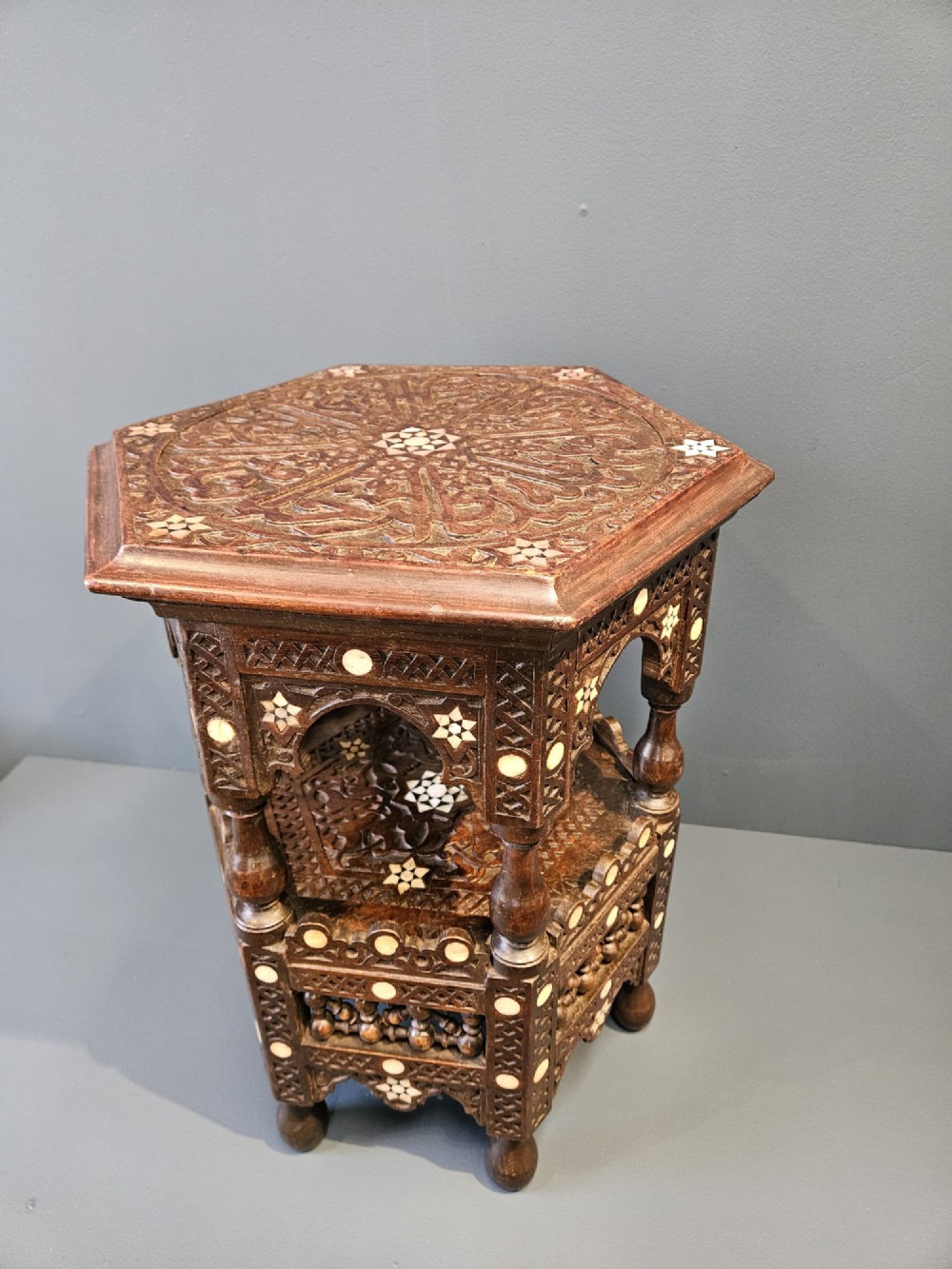 An octagonal dark wood Moorish table featuring carved geometric lattice panels, horseshoe arches, and inlaid bone star motifs. View VI