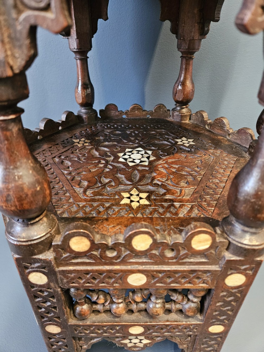 An octagonal dark wood Moorish table featuring carved geometric lattice panels, horseshoe arches, and inlaid bone star motifs. View VII