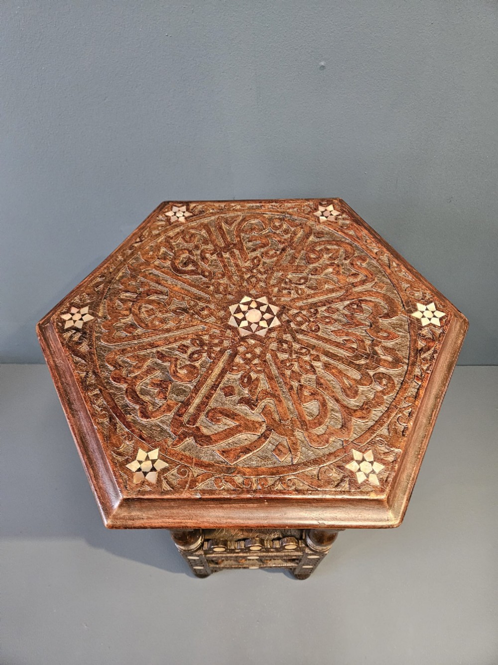 An octagonal dark wood Moorish table featuring carved geometric lattice panels, horseshoe arches, and inlaid bone star motifs. View VIII