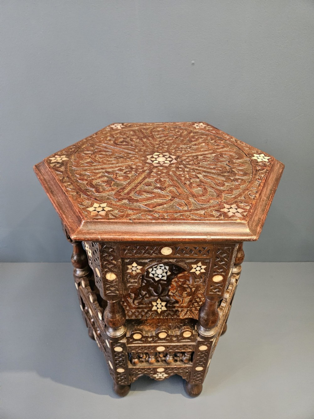 An octagonal dark wood Moorish table featuring carved geometric lattice panels, horseshoe arches, and inlaid bone star motifs. View IX