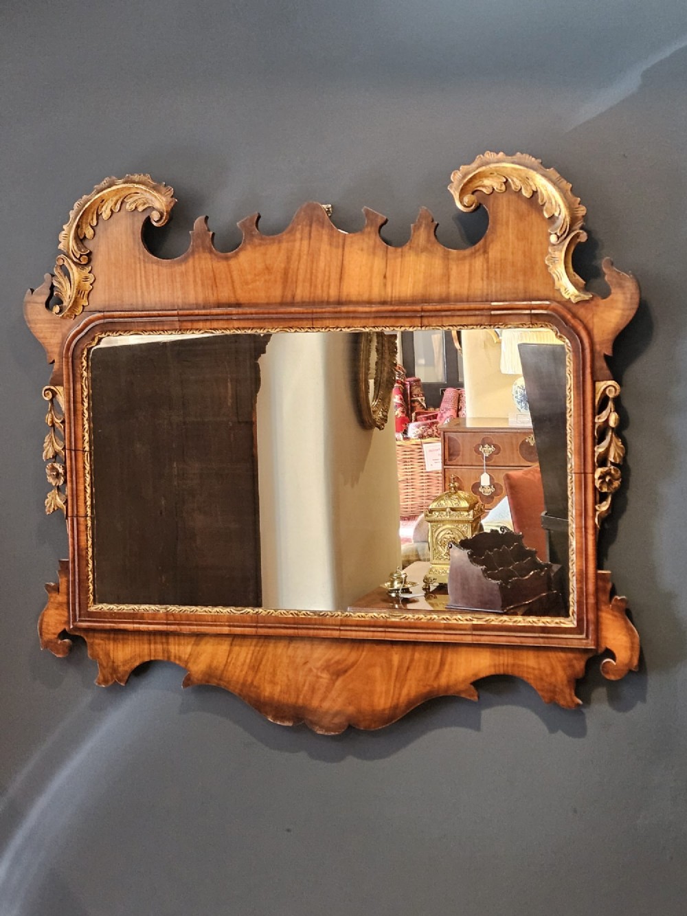 A horizontal George III style landscape wall mirror featuring a shaped mahogany frame accented with carved parcel-gilt leaf scrollwork. View III