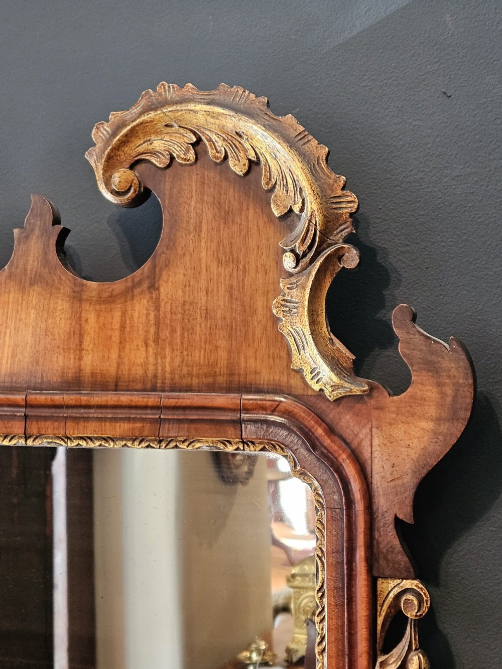 A horizontal George III style landscape wall mirror featuring a shaped mahogany frame accented with carved parcel-gilt leaf scrollwork. View IV