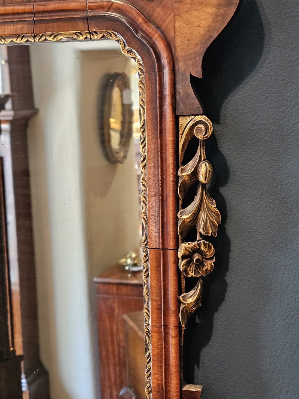 A horizontal George III style landscape wall mirror featuring a shaped mahogany frame accented with carved parcel-gilt leaf scrollwork. View V
