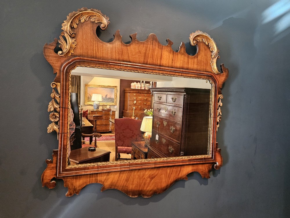 A horizontal George III style landscape wall mirror featuring a shaped mahogany frame accented with carved parcel-gilt leaf scrollwork. View VI