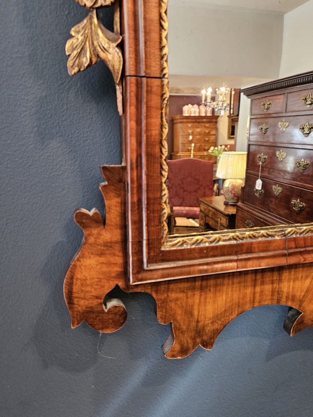 A horizontal George III style landscape wall mirror featuring a shaped mahogany frame accented with carved parcel-gilt leaf scrollwork. View VII