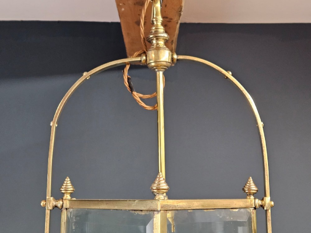An Edwardian brass-framed hall lantern featuring clear glass panels with cut starburst patterns, finial accents, and an arched hanging harness. View II