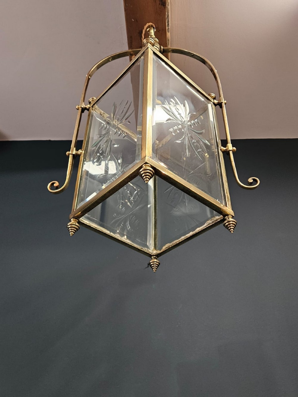 An Edwardian brass-framed hall lantern featuring clear glass panels with cut starburst patterns, finial accents, and an arched hanging harness. View IV