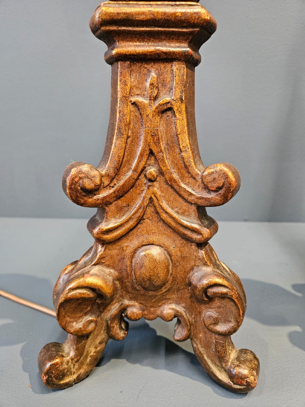 A pair of tall carved timber candlestick table lamps with aged gold gilding and scrolled bases. View II