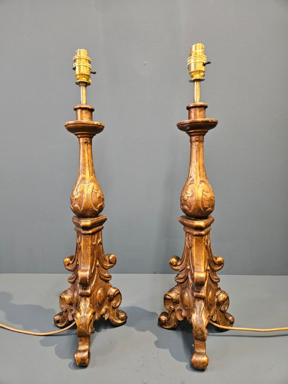 A pair of tall carved timber candlestick table lamps with aged gold gilding and scrolled bases. View III