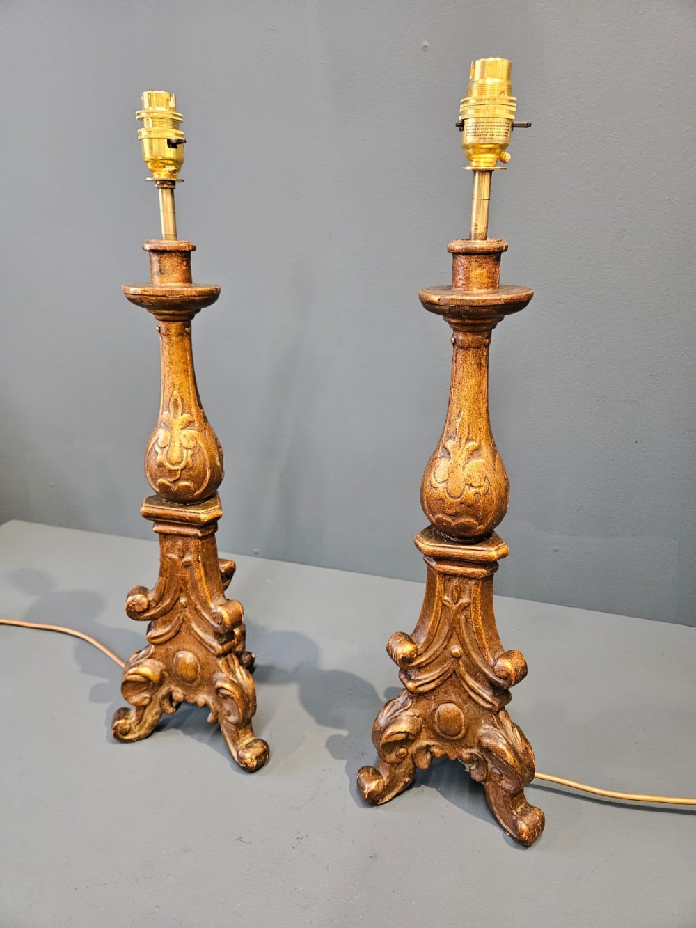 A pair of tall carved timber candlestick table lamps with aged gold gilding and scrolled bases. View IV
