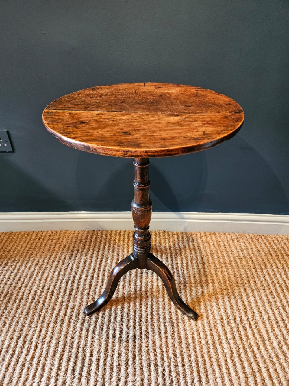 A small George III period oak tripod table featuring a circular top supported by a turned central column and three curved legs. View II