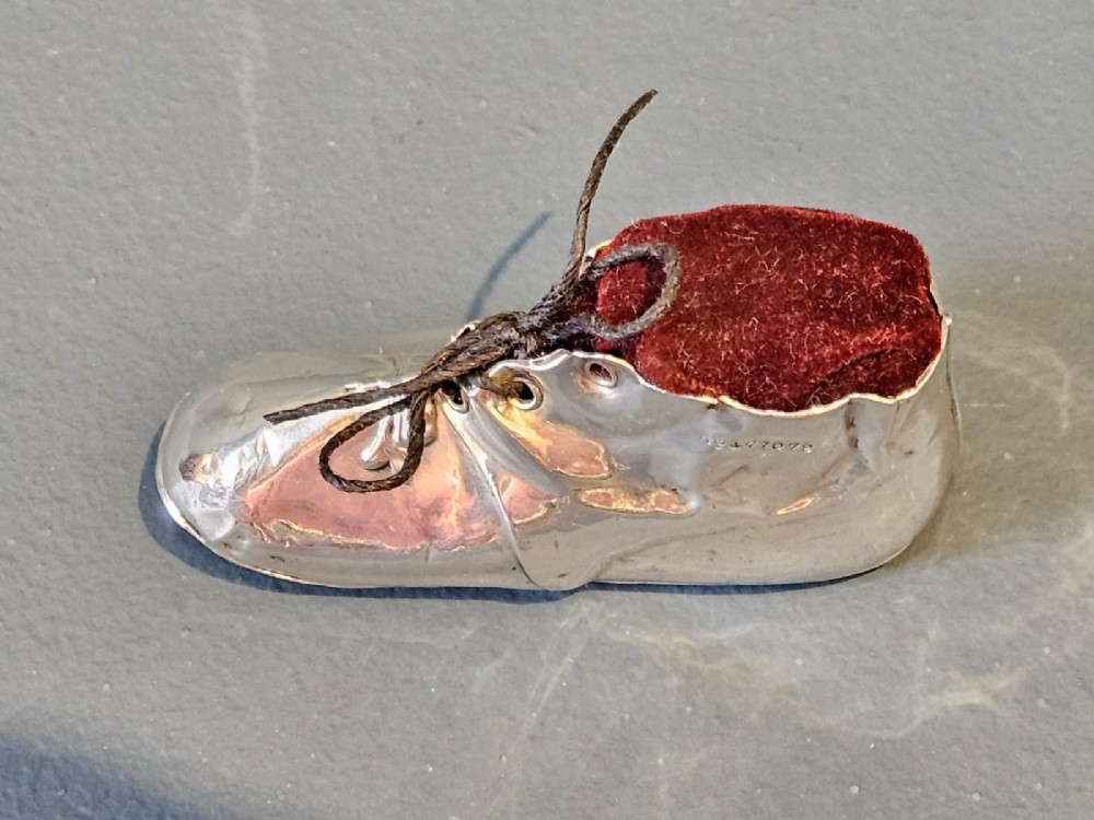 An Edwardian sterling silver pin cushion crafted in the form of a childs boot with a dark red velvet cushion top and cord laces. View IV
